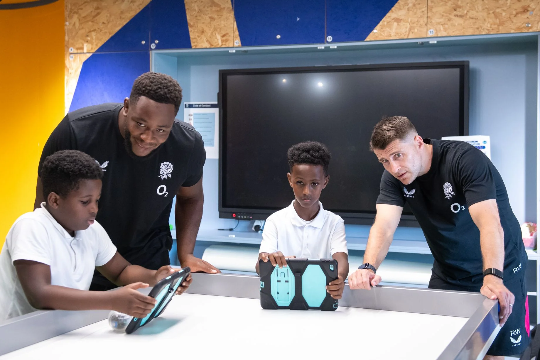 England squad member Manny Iyogun and coach Richard Wigglesworth join children in a digital skills lab